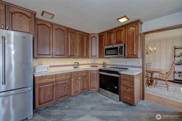 1609 Russell St, Wenatchee, WA 98801 - kitchen with appliances with stainless steel finishes, a chandelier, light countertops, and backsplash