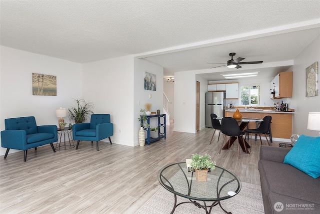 8823 Holly Dr Unit H206, Everett, WA 98208 - living area featuring light wood-style floors, stairway, a textured ceiling, and a ceiling fan
