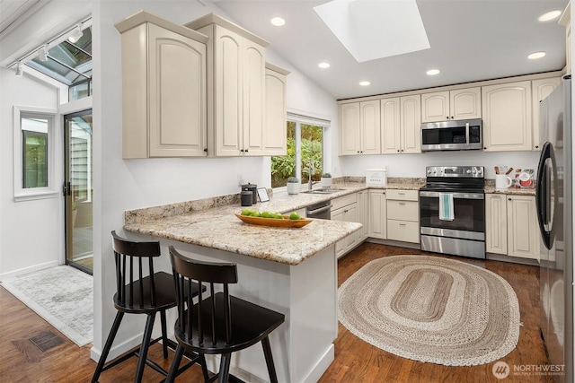 8475 SE 45th St, Mercer Island, WA 98040 - kitchen with stainless steel appliances, a peninsula, a skylight, dark wood-type flooring, and recessed lighting