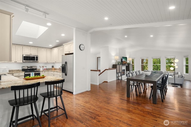 8475 SE 45th St, Mercer Island, WA 98040 - kitchen featuring stainless steel appliances, vaulted ceiling, open floor plan, a skylight, and light stone countertops