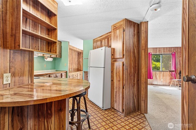 2400 Donovan Unit 67, Bellingham, WA 98225 - kitchen with freestanding refrigerator, wooden walls, open shelves, light flooring, and butcher block counters