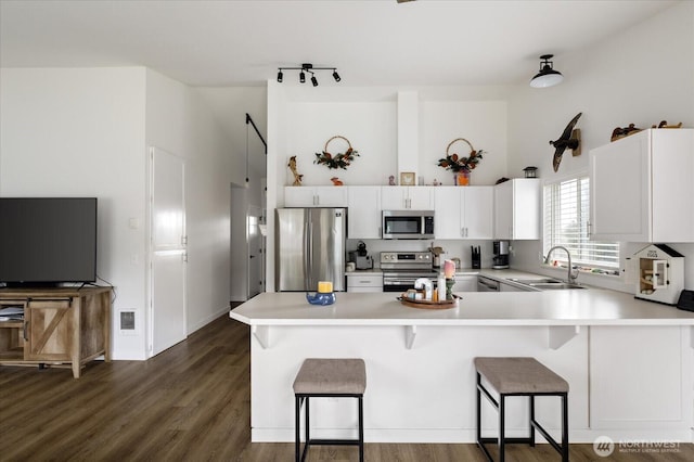 1664 Allyson St, Oak Harbor, WA 98277 - kitchen featuring appliances with stainless steel finishes, light countertops, a peninsula, a breakfast bar area, and white cabinetry