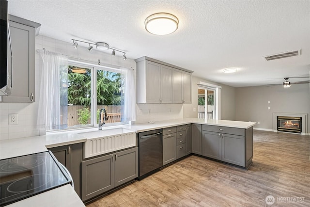 212 SW 2nd Ct, Battle Ground, WA 98604 - kitchen featuring gray cabinetry, dishwasher, a peninsula, tasteful backsplash, and light wood-style flooring