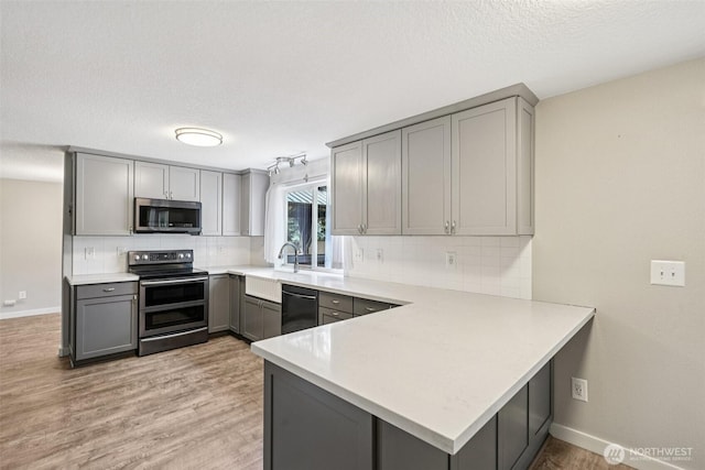 212 SW 2nd Ct, Battle Ground, WA 98604 - kitchen with appliances with stainless steel finishes, gray cabinets, a peninsula, light countertops, and a textured ceiling
