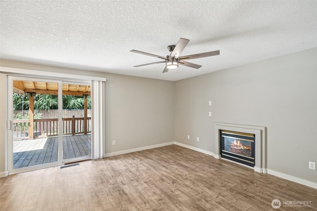 212 SW 2nd Ct, Battle Ground, WA 98604 - unfurnished living room featuring wood finished floors, a ceiling fan, a glass covered fireplace, and a textured ceiling