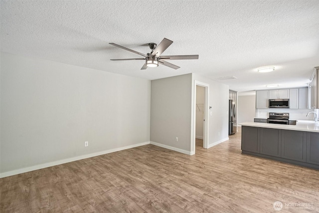 212 SW 2nd Ct, Battle Ground, WA 98604 - kitchen with appliances with stainless steel finishes, open floor plan, light wood-style flooring, light countertops, and a textured ceiling