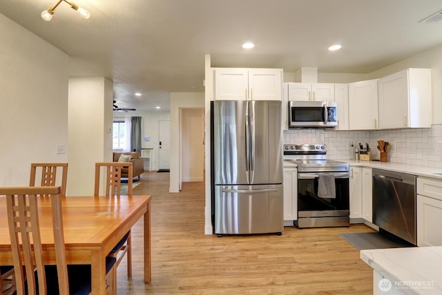 302 126th St S, Parkland, WA 98444 - kitchen featuring stainless steel appliances, light wood finished floors, backsplash, white cabinets, and light countertops