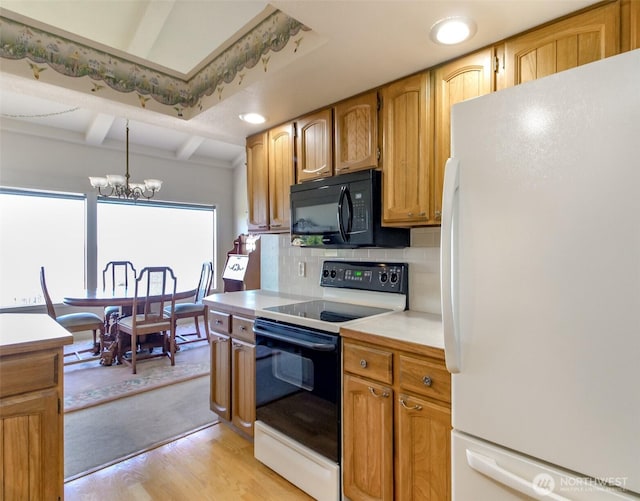 28313 Redondo Way S Unit 304, Des Moines, WA 98198 - kitchen with freestanding refrigerator, range with electric stovetop, black microwave, a chandelier, and tasteful backsplash