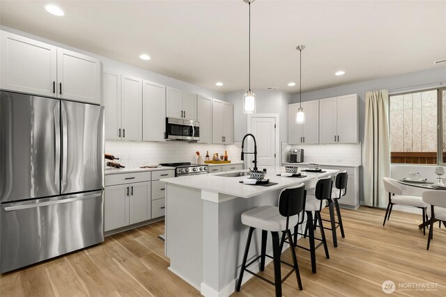 12433 SE 256th Pl Unit 4, Kent, WA 98030 - kitchen with stainless steel appliances, backsplash, a kitchen breakfast bar, an island with sink, and light countertops