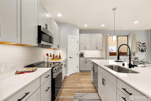 12433 SE 256th Pl Unit 4, Kent, WA 98030 - kitchen featuring stainless steel appliances, light wood-style flooring, light countertops, decorative light fixtures, and tasteful backsplash