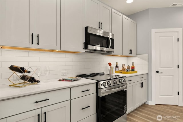 12433 SE 256th Pl Unit 4, Kent, WA 98030 - kitchen featuring appliances with stainless steel finishes, light countertops, light wood-style floors, and backsplash