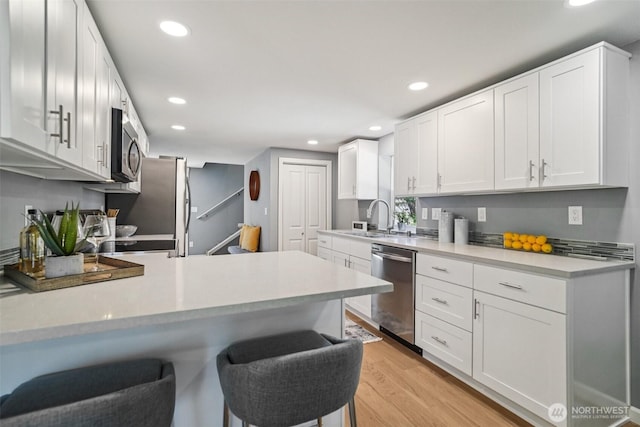 14427 156th Ave SE, Renton, WA 98059 - kitchen featuring stainless steel appliances, light countertops, recessed lighting, light wood-style flooring, and a kitchen breakfast bar