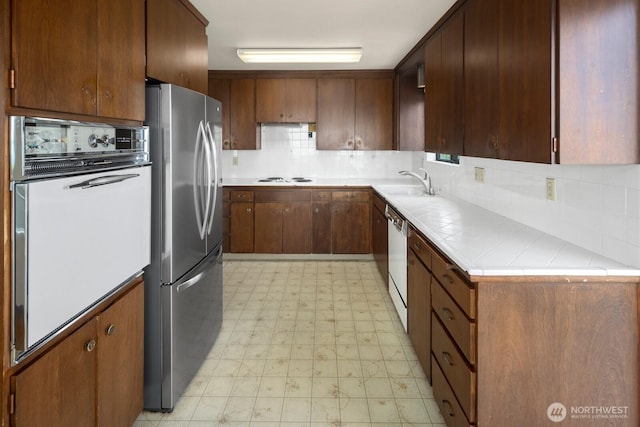 5621 SW Manning St, Seattle, WA 98116 - kitchen with white appliances, light floors, tasteful backsplash, and tile countertops