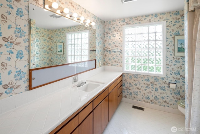 5621 SW Manning St, Seattle, WA 98116 - bathroom featuring plenty of natural light, vanity, wallpapered walls, and tile patterned floors