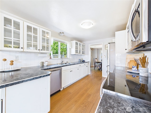 1006 E Harrison St, Tacoma, WA 98404 - kitchen featuring appliances with stainless steel finishes, light wood-style flooring, white cabinetry, glass insert cabinets, and tasteful backsplash