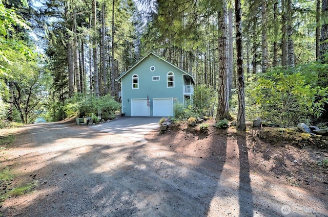 250 E Crest Ln, Grapeview, WA 98546 - view of side of property with an attached garage, driveway, and a wooded view