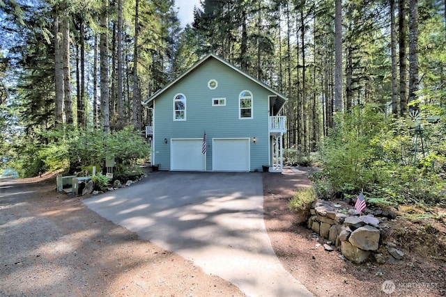 250 E Crest Ln, Grapeview, WA 98546 - view of side of property featuring asphalt driveway, an attached garage, and a wooded view