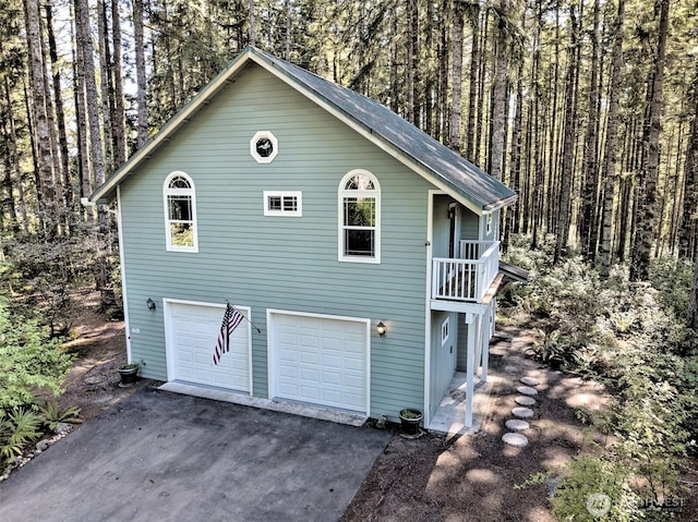 250 E Crest Ln, Grapeview, WA 98546 - view of home's exterior with driveway, an attached garage, and a view of trees