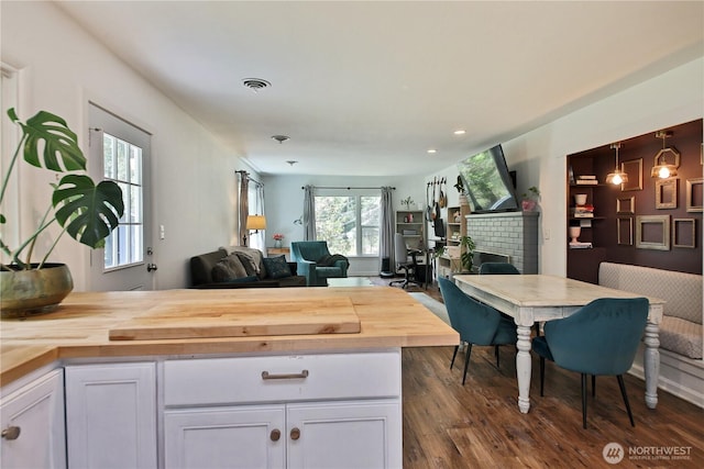 4907 Pinewood Cir, Langley, WA 98260 - kitchen with wood counters, open floor plan, white cabinetry, dark wood-style floors, and a fireplace