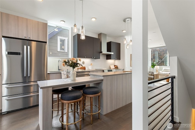 410A 10th Ave E, Seattle, WA 98102 - kitchen with stainless steel refrigerator, wall chimney range hood, dark wood-style flooring, a kitchen breakfast bar, and modern cabinets