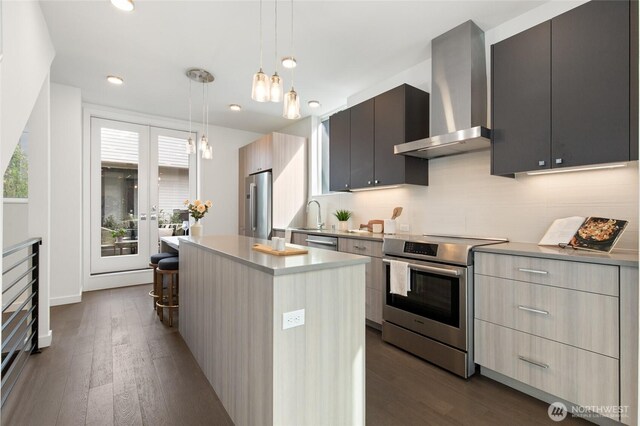 410A 10th Ave E, Seattle, WA 98102 - kitchen with stainless steel appliances, wall chimney range hood, modern cabinets, a center island, and a kitchen bar
