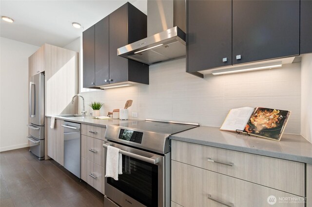 410A 10th Ave E, Seattle, WA 98102 - kitchen featuring appliances with stainless steel finishes, wall chimney range hood, tasteful backsplash, and dark wood-style flooring