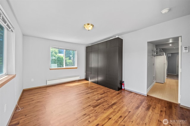 610 128th St S, Tacoma, WA 98444 - unfurnished bedroom with baseboard heating, wood finished floors, freestanding refrigerator, and a closet