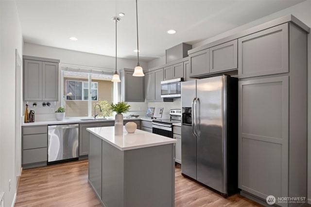 3312 156th St SW Unit E4, Lynnwood, WA 98087 - kitchen featuring appliances with stainless steel finishes, gray cabinets, light wood-style flooring, light countertops, and a center island
