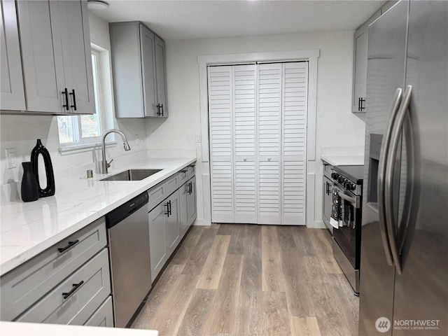 12706 94th Ave E, Puyallup, WA 98373 - kitchen with appliances with stainless steel finishes, gray cabinets, light wood-style flooring, and light stone countertops