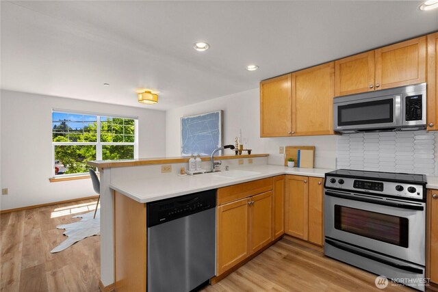 2820 E Madison St Unit 204, Seattle, WA 98112 - kitchen featuring stainless steel appliances, a peninsula, light countertops, light wood-type flooring, and recessed lighting