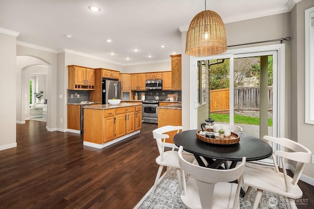 3606 Monterey Ct NE, Renton, WA 98056 - kitchen featuring appliances with stainless steel finishes, a kitchen island, arched walkways, tasteful backsplash, and dark wood-style flooring