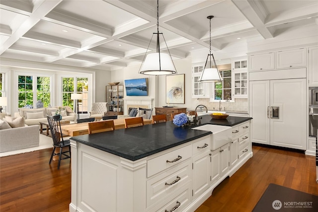 2001 Broadmoor Dr E, Seattle, WA 98112 - kitchen featuring dark countertops, paneled built in fridge, dark wood finished floors, a center island with sink, and white cabinets