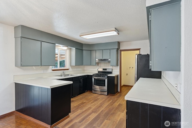 2598 25th Loop SE, Lacey, WA 98503 - kitchen featuring stainless steel appliances, a textured ceiling, light countertops, under cabinet range hood, and a peninsula