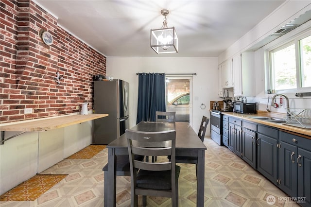 1608 Laura St, Aberdeen, WA 98520 - kitchen featuring stainless steel appliances, plenty of natural light, brick wall, blue cabinets, and hanging light fixtures