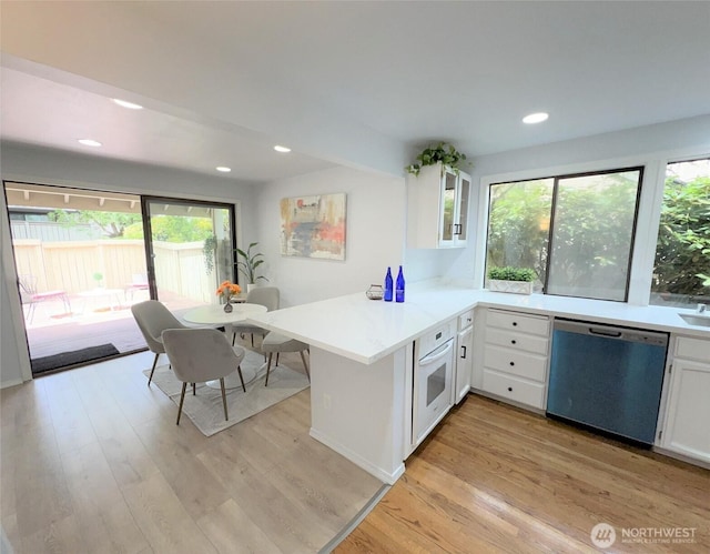 1711 159th Pl NE Unit 29, Bellevue, WA 98008 - kitchen with stainless steel dishwasher, a peninsula, white cabinetry, light wood-type flooring, and white oven