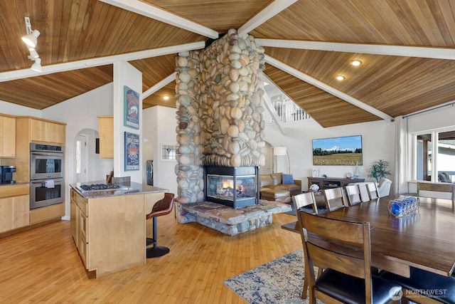 6926 Holeman Ave, Blaine, WA 98230 - dining room with a wood ceiling with exposed beams, a stone fireplace, high vaulted ceiling, arched walkways, and light wood-style flooring