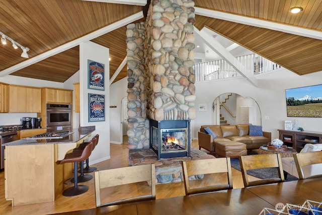 6926 Holeman Ave, Blaine, WA 98230 - living area with a wood ceiling with exposed beams, a fireplace, wood finished floors, high vaulted ceiling, and arched walkways