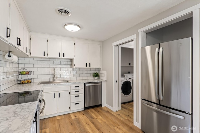 4502 223rd St SW, Mountlake Terrace, WA 98043 - kitchen featuring stainless steel appliances, tasteful backsplash, white cabinetry, light wood-style flooring, and washing machine and clothes dryer