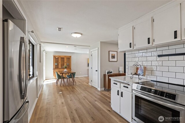 4502 223rd St SW, Mountlake Terrace, WA 98043 - kitchen with appliances with stainless steel finishes, decorative backsplash, white cabinets, light wood-style flooring, and light stone countertops