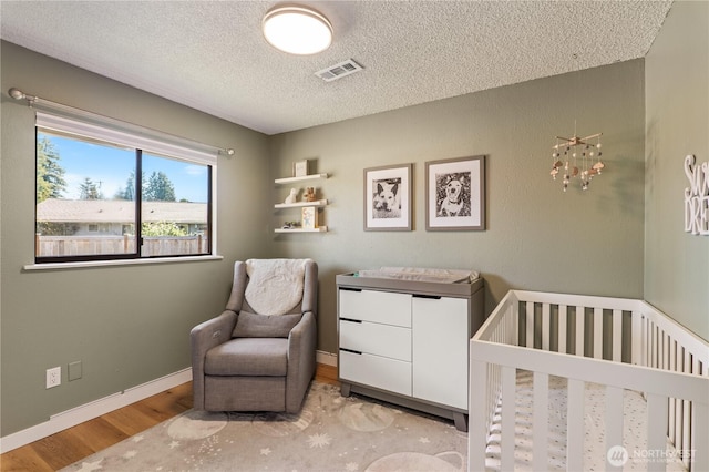 4502 223rd St SW, Mountlake Terrace, WA 98043 - bedroom with wood finished floors, a textured ceiling, and a nursery area
