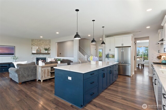 381 E Benson Ridge Rd, Grapeview, WA 98546 - kitchen featuring stainless steel appliances, blue cabinets, dark wood-type flooring, white cabinets, and a fireplace