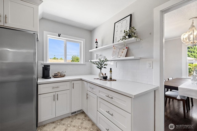 213 S 58th St, Tacoma, WA 98408 - kitchen with stainless steel fridge, light countertops, tasteful backsplash, a chandelier, and open shelves