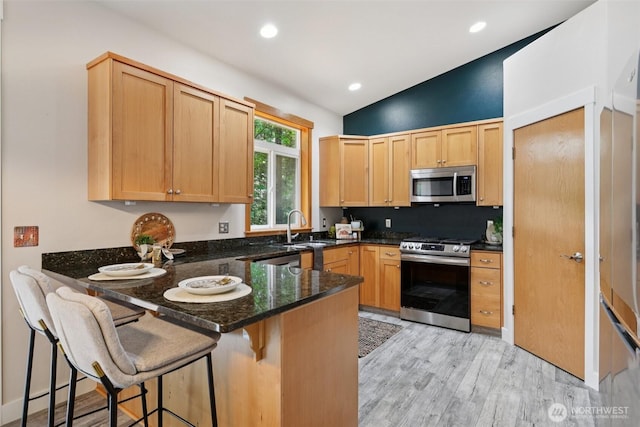 49 Cascade Ln, Bellingham, WA 98229 - kitchen featuring a peninsula, stainless steel appliances, light wood-style floors, light brown cabinetry, and dark stone counters