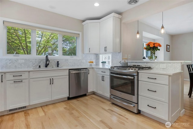 7709 NE 170th St, Kenmore, WA 98028 - kitchen with stainless steel appliances, a peninsula, light countertops, decorative backsplash, and light wood-style flooring