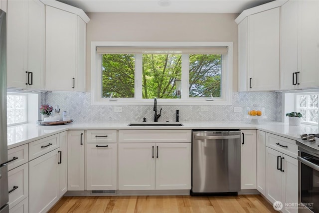 7709 NE 170th St, Kenmore, WA 98028 - kitchen with stainless steel appliances, light countertops, decorative backsplash, white cabinetry, and light wood-type flooring