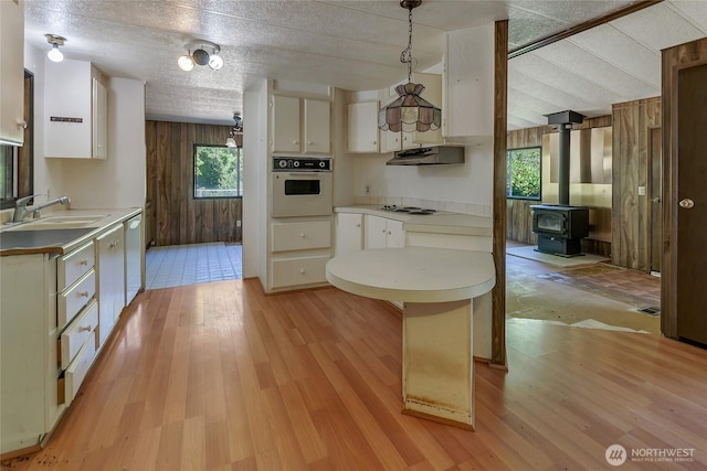151 Dietz Dr, Quilcene, WA 98376 - kitchen with white appliances, wood walls, under cabinet range hood, light countertops, and light wood finished floors