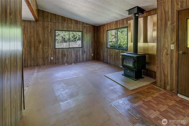 151 Dietz Dr, Quilcene, WA 98376 - unfurnished living room featuring vaulted ceiling, wood walls, a wood stove, and concrete floors