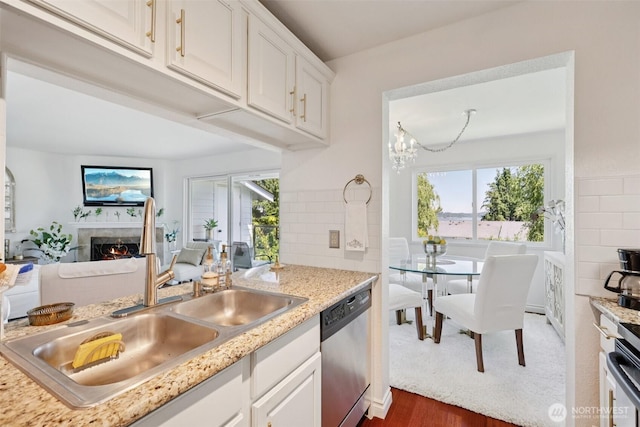 4181 W Lake Sammamish Pkwy SE Unit B301, Bellevue, WA 98008 - kitchen with stainless steel dishwasher, wood finished floors, a tiled fireplace, white cabinetry, and a chandelier