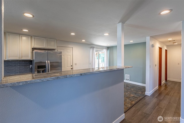 406 Brown Way SE, Orting, WA 98360 - kitchen with stainless steel fridge, a peninsula, recessed lighting, dark wood-style floors, and light stone counters