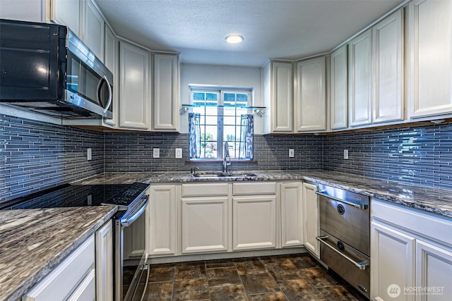 406 Brown Way SE, Orting, WA 98360 - kitchen with appliances with stainless steel finishes, dark stone counters, tasteful backsplash, a textured ceiling, and white cabinetry